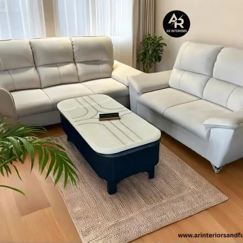 Two cream faux-leather sofas arranged around a navy-and-white coffee table on a jute rug, with a potted palm in the foreground.