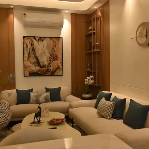 Two curved cream boucle sofas with teal and houndstooth cushions sit under an oil painting of a saxophone player