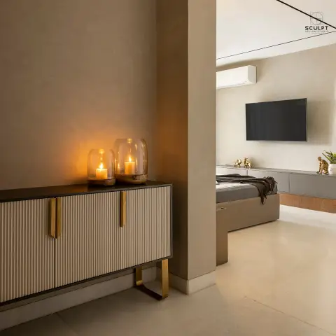 Two glass hurricane lanterns burn on a fluted beige console with brass strap handles