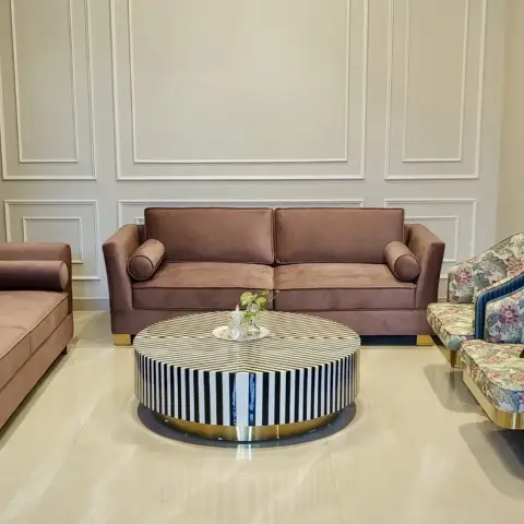 Two mauve velvet sofas on brass block feet facing each other across a round black-and-white striped inlay table with a brass base ring