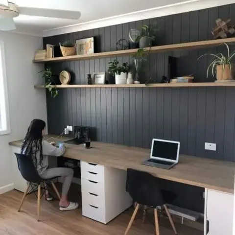 Two-person home study running the full length of a charcoal vertical shiplap wall, with a continuous oak desk top carried on white drawer towers