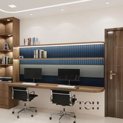 Two-seat floating home-office desk with dual monitors under a navy fluted-panelled wall with backlit open wood shelving, beside a dark wood-veneer door.