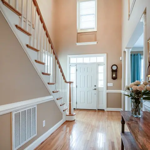 Two-story entrance foyer with a wood-and-white staircase, a glass-paned front door flanked by sconces