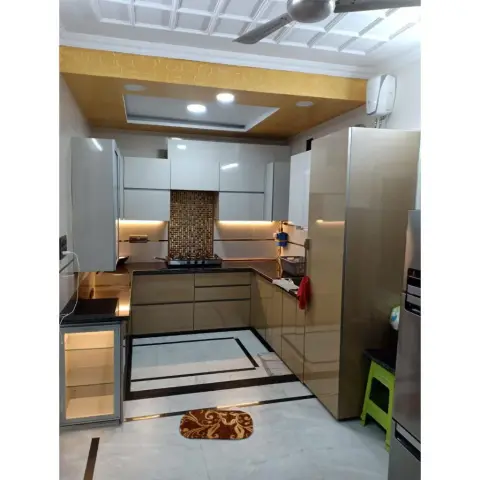 U-shaped kitchen in beige high-gloss shutters with a black granite counter and a gold glass-mosaic panel behind the hob, under-cabinet strip lighting