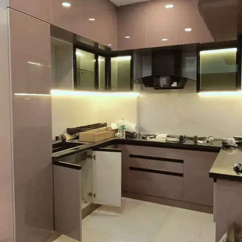 U-shaped kitchen in dusty mauve high-gloss just after installation, with black granite counters, tinted glass wall units lit from inside