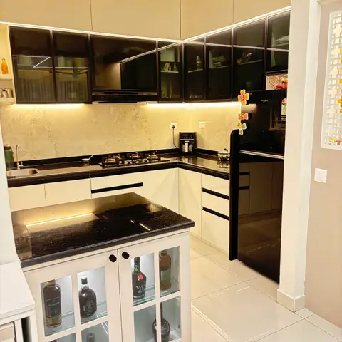 U-shaped kitchen with cream gloss cabinetry and black granite counters, centred on an island topped with the same granite and a glass-door bar cabinet