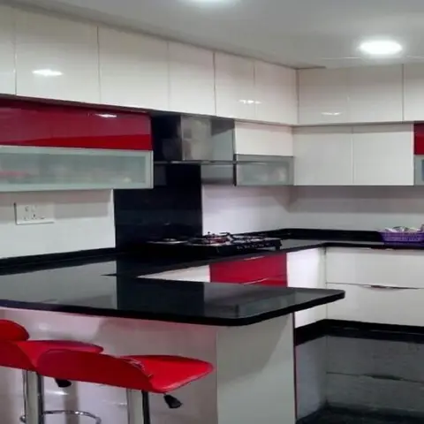 U-shaped kitchen with glossy red-and-white cabinets, black granite countertops, a red breakfast bar with matching stools, and a black chimney hood.