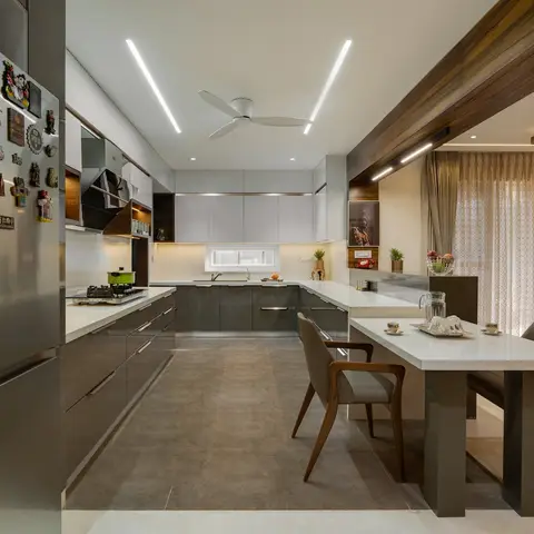 U-shaped kitchen with glossy taupe-grey cabinets and a white stone countertop extending into a breakfast table