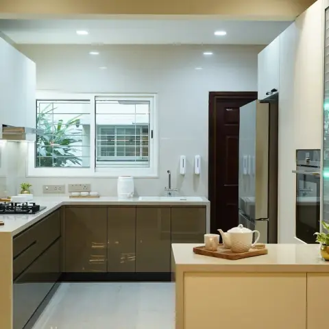 U-shaped kitchen with olive-grey high-gloss base units under cream quartz counters and white wall cabinets