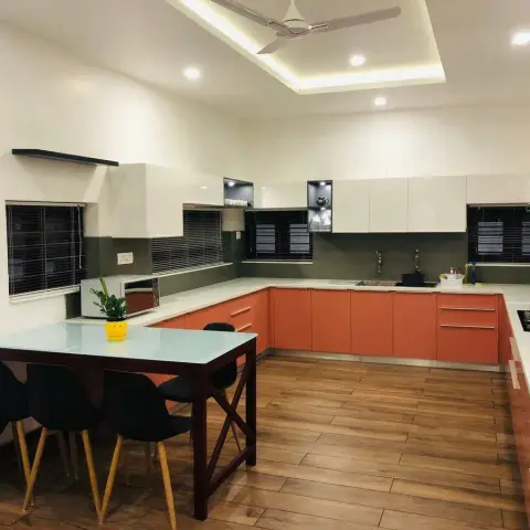 U-shaped kitchen with terracotta-orange gloss base units, off-white wall cabinets with two open black display niches, an olive-grey dado