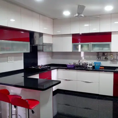 U-shaped modular kitchen with glossy red-and-white cabinetry, black granite counters, a peninsula breakfast counter with red stools