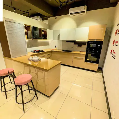 U-shaped modular kitchen with glossy beige shutters, marble-effect backsplash, a built-in oven and microwave tower