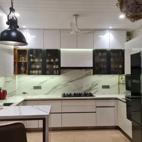 U-shaped white gloss kitchen wrapped in a book-matched Statuario slab dado, with black-framed glass crockery units either side of the hob