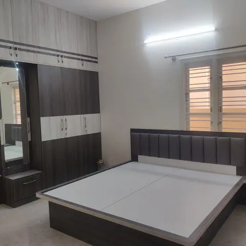 Under-furnished bedroom with a two-tone wardrobe and integrated mirrored dresser unit