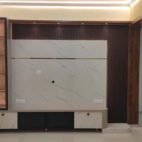 Unfurnished flat hall with a marble-look TV back panel split by a brass inlay line, walnut fluted panelling carrying up the return wall
