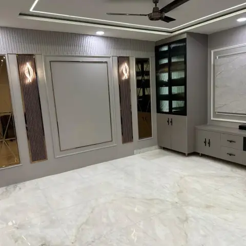 Unfurnished grey living room where fluted panels, bronze-tint bevelled mirror strips and a moulded blank frame face a marble-slab TV backdrop over a low