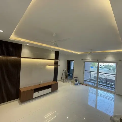 Unfurnished hall at handover with a dark fluted-panel TV wall wrapping a marble-look tile backdrop and a two-tone floating console