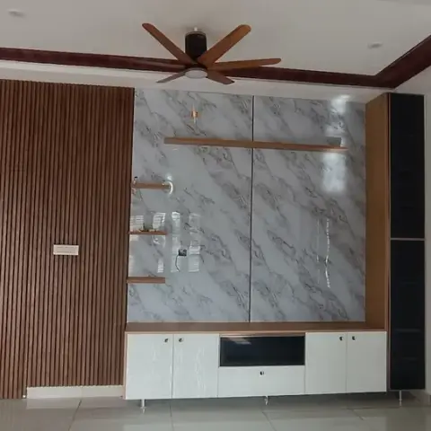 Unfurnished hall of a new house where a floor-to-ceiling teak fluted panel meets a glossy white-and-grey marble-look TV slab with three staggered wooden