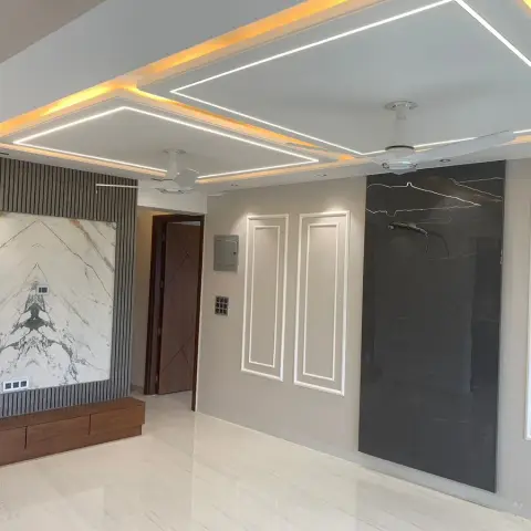 Unfurnished living hall with a book-matched white marble TV backdrop set into grey fluted panelling over a floating walnut drawer console