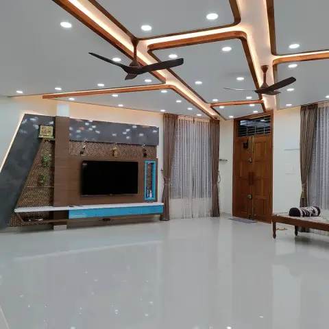 Unfurnished living room under an angular stepped false ceiling ribbed in wood-finish profiles and cove light around two dark fans