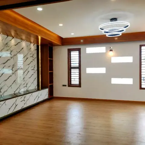Unfurnished living room with a book-matched marble TV feature wall, wood beam ceiling trim, and a tiered ring pendant chandelier.