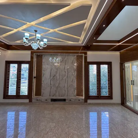 Unfurnished living room with a geometric wood-trimmed cove-lit false ceiling, a book-matched marble feature wall with built-in drawers