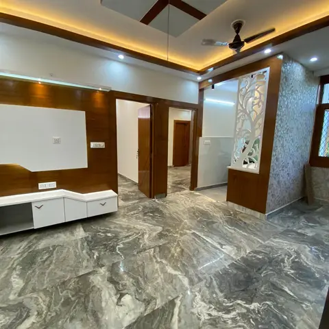 Unfurnished living room with dramatic grey-veined marble flooring, a wood-trimmed geometric pop ceiling and a carved white jaali partition screen