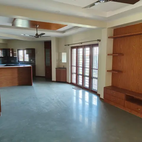 Unfurnished open-plan living-kitchen area with a wood-panelled TV wall, an open kitchen counter, and French balcony doors.