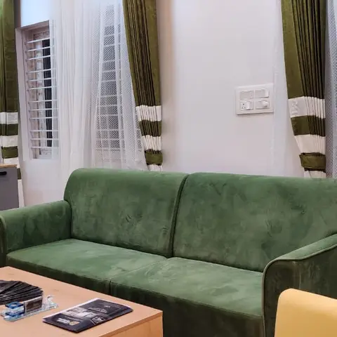 Vertical wide-angle view of the same green velvet sofa and mustard armchair living room
