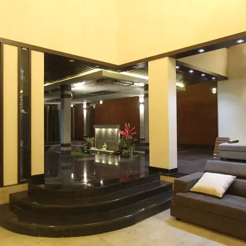 Villa living area with grey L-shaped sofas beside an open indoor courtyard water feature framed by black granite steps