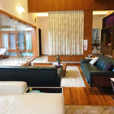Villa living room where dark green and cream leather sofas sit on a raised teak platform around a low wooden table