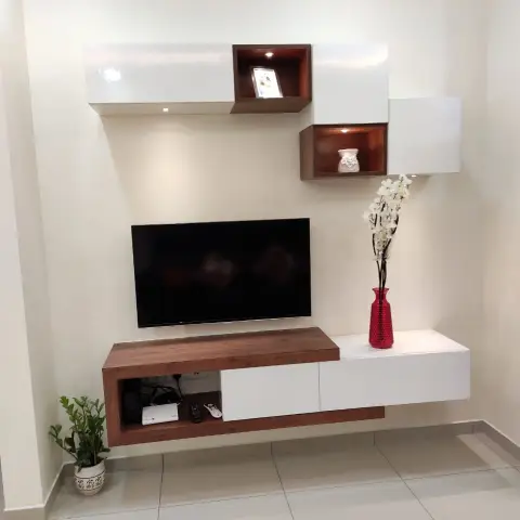 Wall-hung white-gloss and walnut TV unit with two lit open display boxes staggered above a 43-inch TV, on a bare cream wall over glossy white tile.