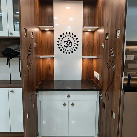 Wall-mounted pooja unit with walnut-finish cabinetry, carved jaali door panels, a backlit Om jaali medallion
