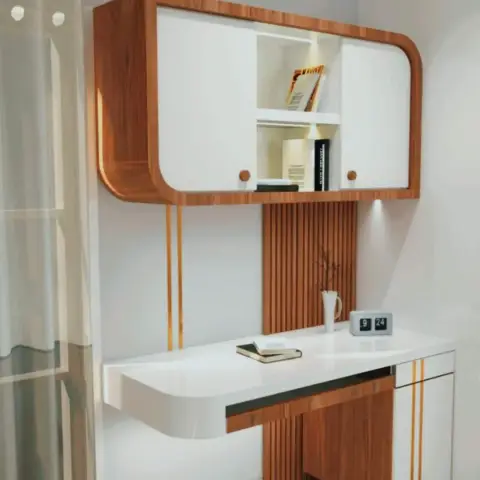 Wall-mounted study desk unit with rounded teak-and-white cabinetry, a fluted panel backdrop and thin gold trim accents