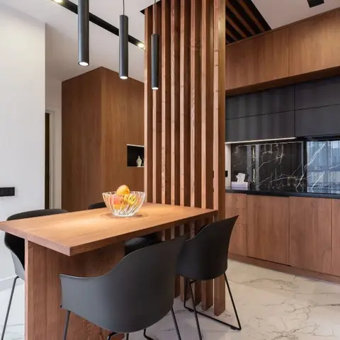 Walnut dining nook screened by a vertical wood-slat partition, with a black marble kitchen backsplash visible behind.