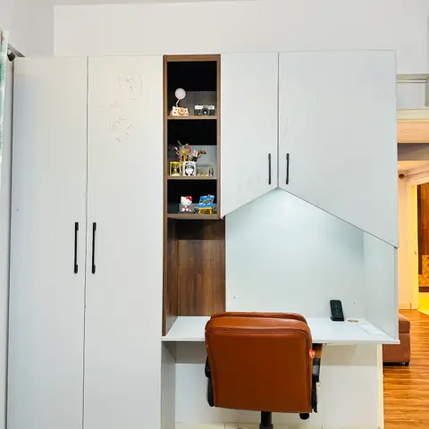 Wardrobe and study desk combo in a child's room, with a small open display niche holding toys and stationery, a brown leather office chair