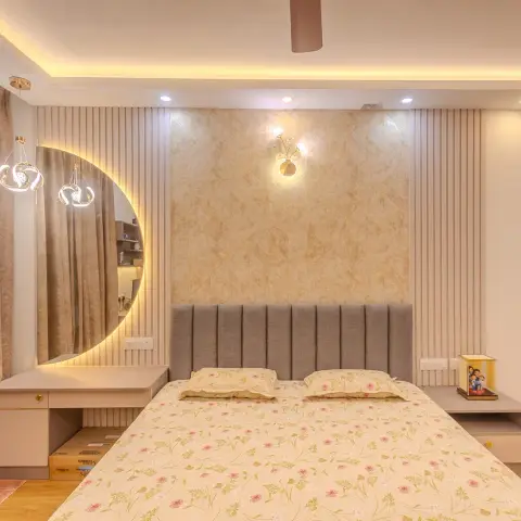 Warm-lit bedroom with a grey channel-tufted headboard against a beige damask-textured panel, cream fluted panelling running out on both sides