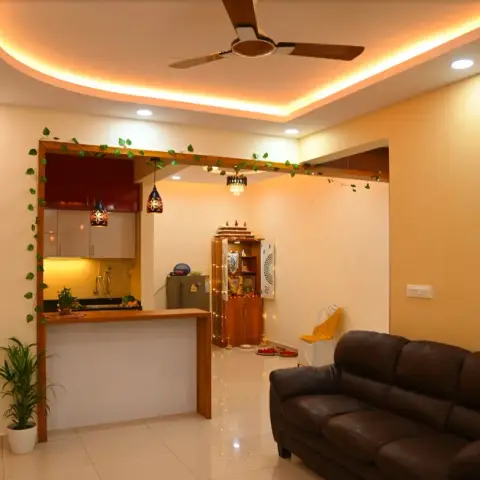 Warm-lit open-plan flat with a brown leather sofa in front, an open kitchen behind a teak-edged breakfast counter hung with two Moroccan-style lanterns