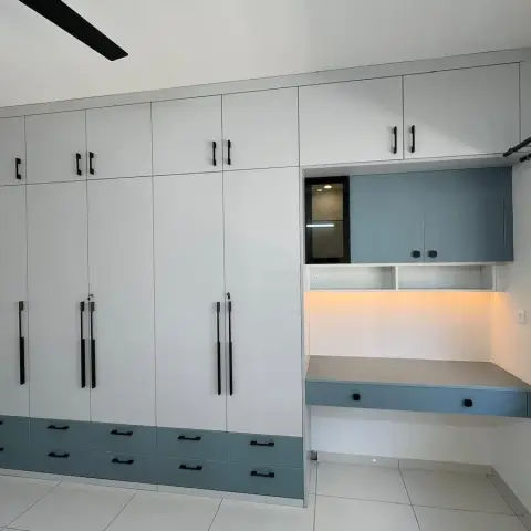 White and slate-blue laminate wardrobe wall with an integrated floating study desk lit by a warm profile light strip.