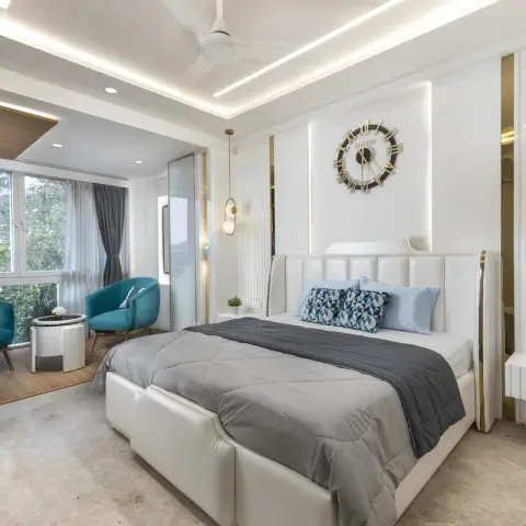 White bedroom with a brass-edged channel-tufted headboard set into a backlit recess carrying an oversized Roman-numeral clock