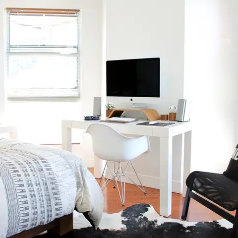 White bedroom with a vertical timber-plank headboard wall and a bare-bulb pendant dropped beside the bed