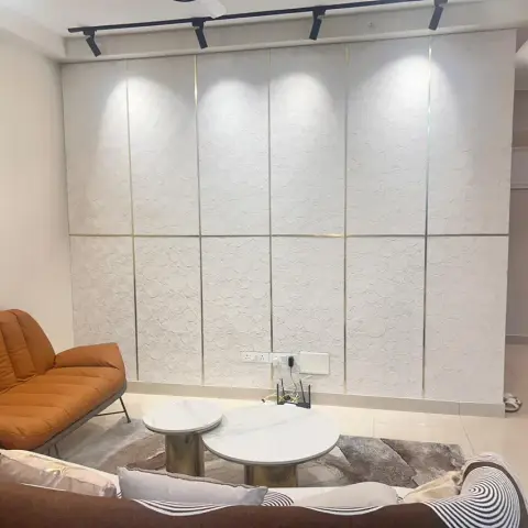 White circular-relief textured panels split by thin brass reveal strips and grazed by black track spots