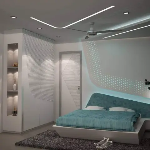 White corner wardrobe with fine-grooved shutters and lit display niches faces a low platform bed in teal