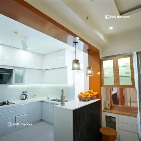 White gloss L-shaped kitchen with a fluted-panel breakfast counter, geometric pendant lights