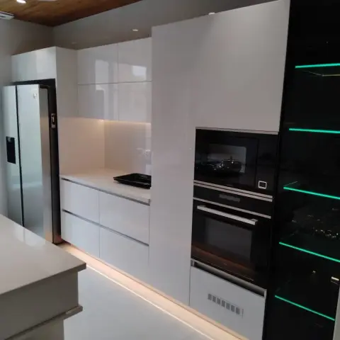 White handleless gloss kitchen with a hob island, a tall built-in oven-microwave-warmer stack