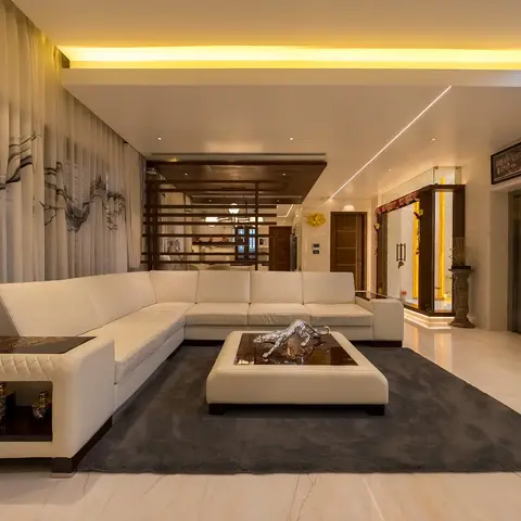 White leather L-shaped sectional sofa around a marble-topped coffee table with a silver leopard sculpture, grey rug