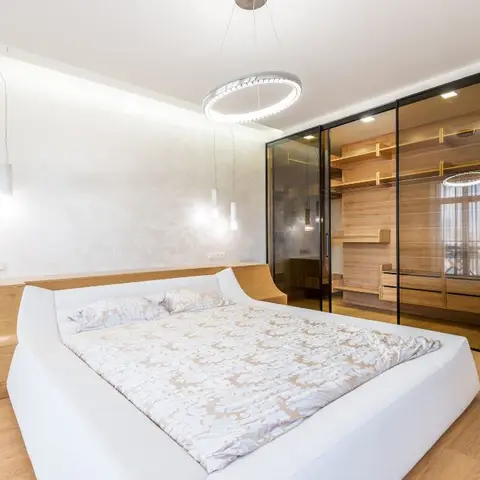 White leather platform bed backed by an oak headboard that runs on into a full-length side console