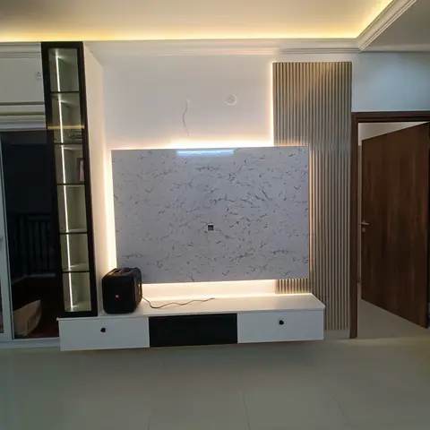 White marble-slab TV feature wall with a gold-toned fluted side panel and cove lighting, TV not yet mounted