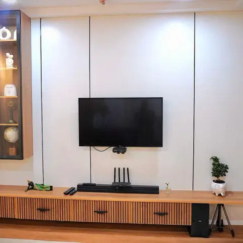 White panelled TV wall with slim black shadow grooves over a long light-oak console with fluted drawer fronts