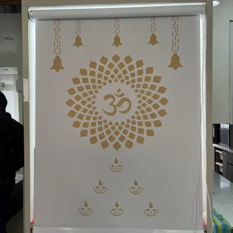 White pooja cabinet fitted with a printed roller-blind shutter featuring an Om motif, bells, and diya patterns, with storage drawers below.